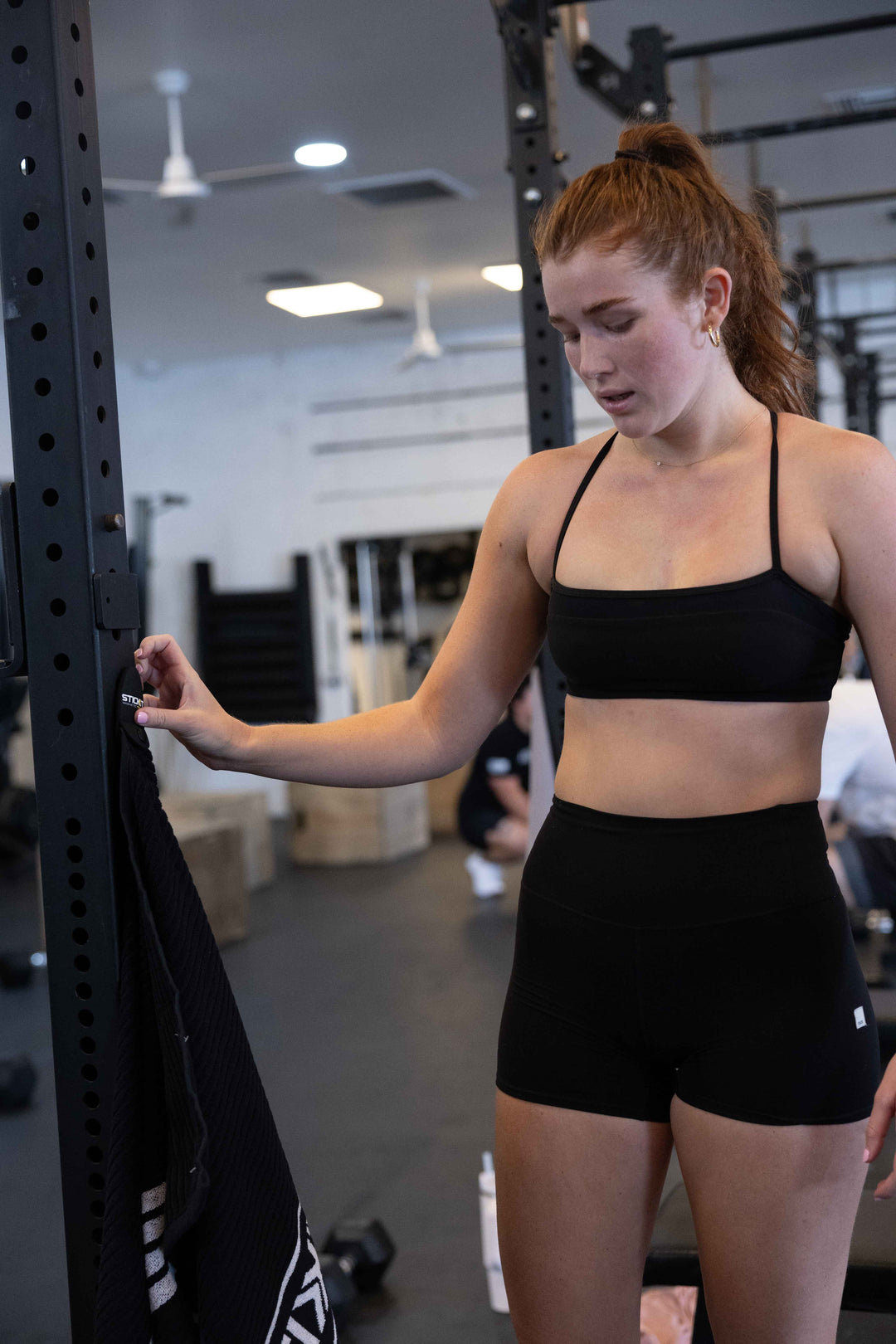 Black sports bra and high-waisted shorts on a woman in a gym setting, perfect for workouts and fitness activities.