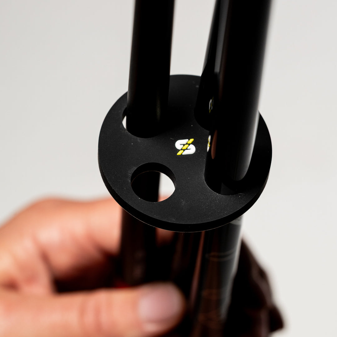 Black aluminum tripod head with a logo, featuring three attachment holes for stability and support.