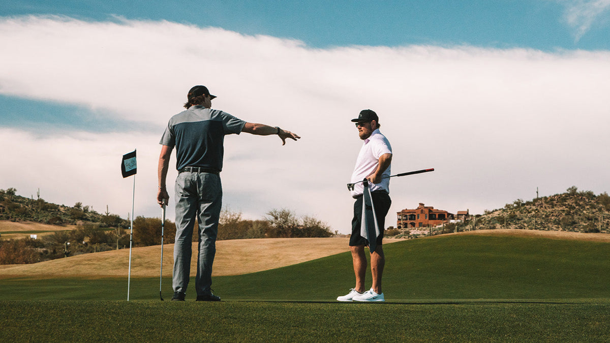 Golf apparel in grey and white; performance polo shirts and tailored pants on the course with a scenic backdrop.