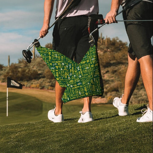 Green golf towel with white and yellow text, made of microfiber, stylish and functional for golfers on the course.