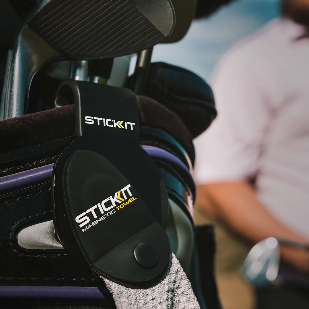 Black StickIt magnetic towel holder with white logo, designed for easy attachment to golf bags and accessories.