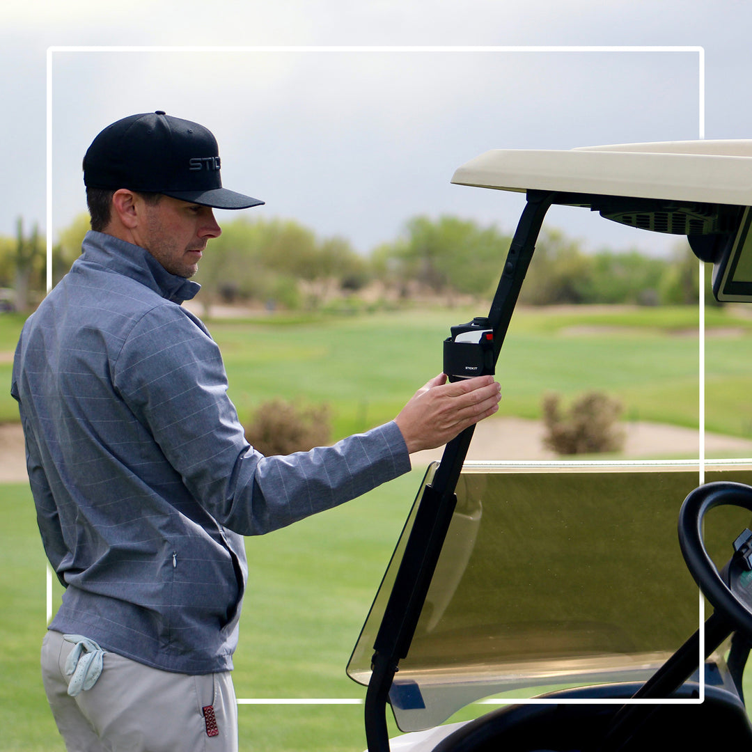 Men's gray golf jacket with hood, lightweight fabric, worn by golfer holding a golf club on a course.