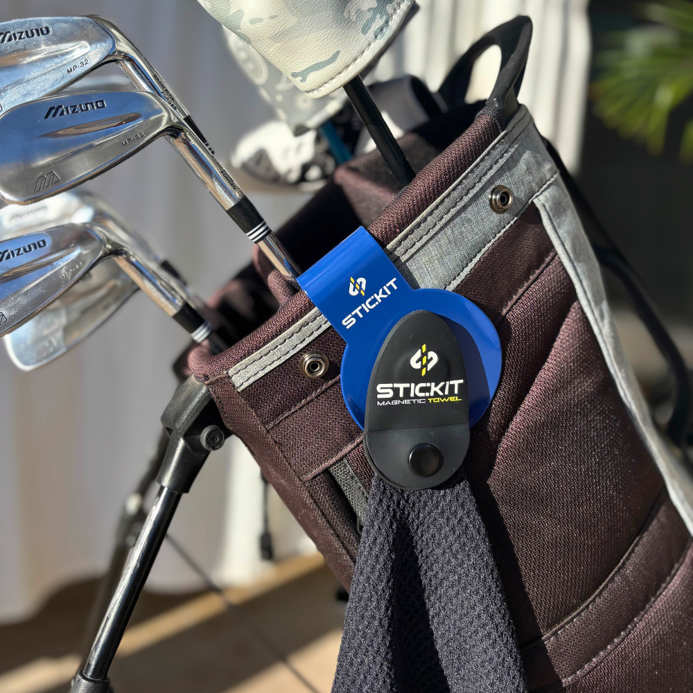Blue STICKIT magnetic golf towel hanging from a dark fabric golf bag with Mizuno clubs. Ideal for on-the-go golfers.