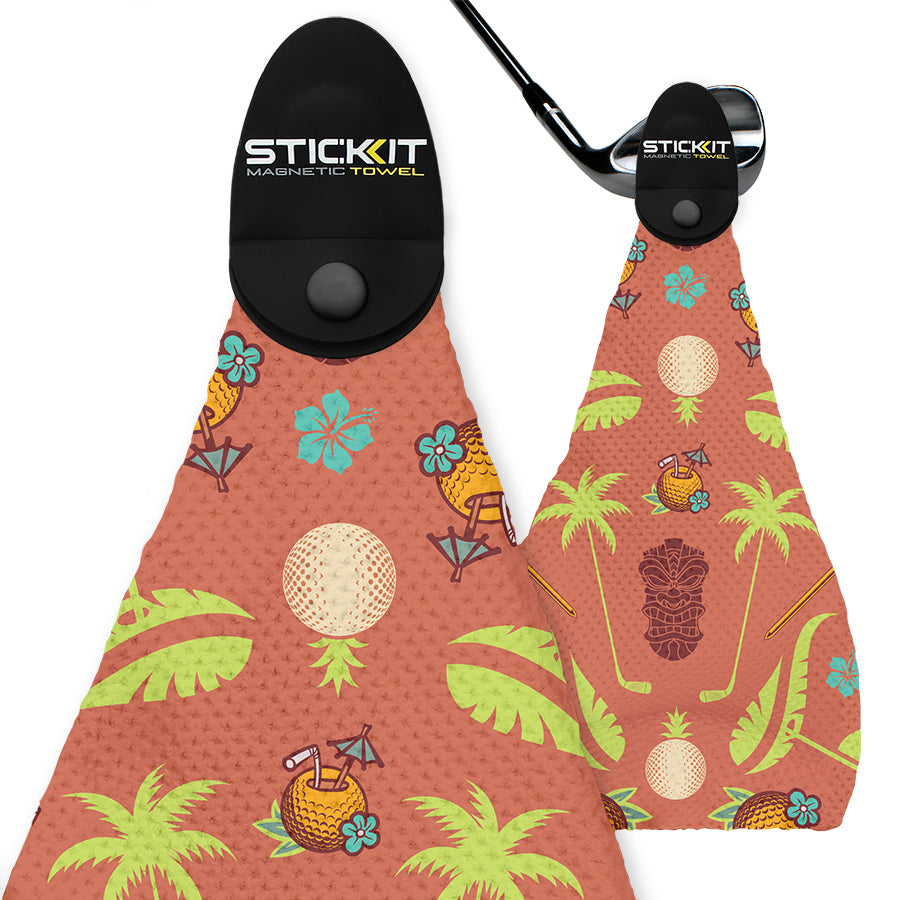 Coral magnetic golf towel with tropical print, featuring pineapples, palm trees, and golf motifs in vibrant colors.