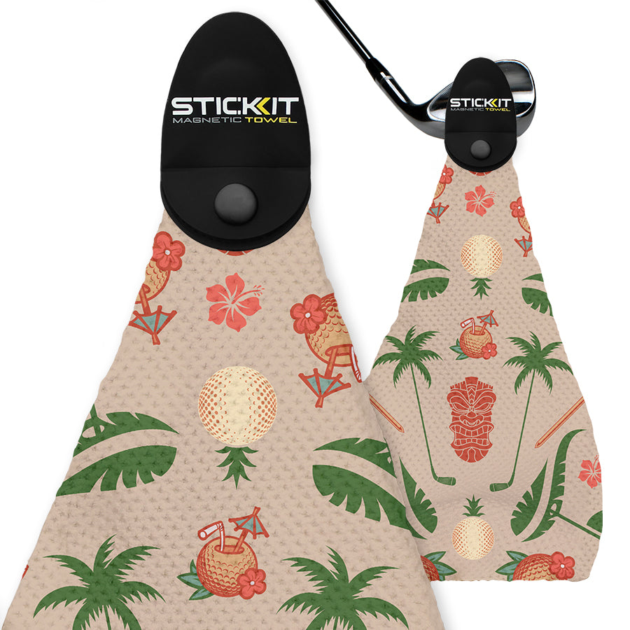 Beige golf towel with tropical print, featuring palm trees, tiki masks, and golf balls, designed with a magnetic clip.