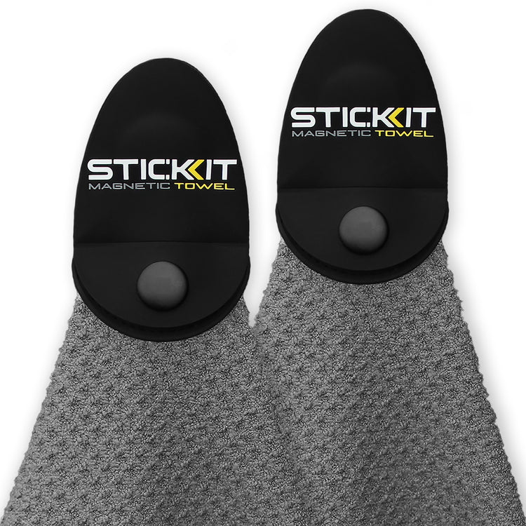 Gray textured towel with black magnetic holder, branded "STICKIT," perfect for workouts and outdoor activities.