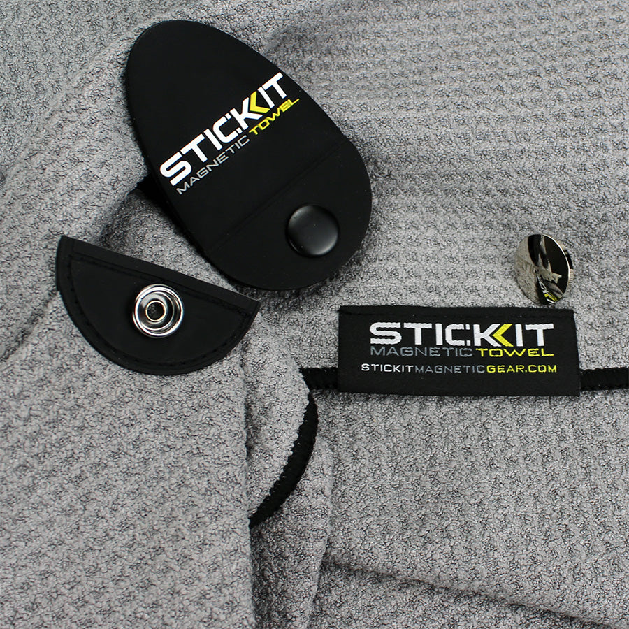 Gray Stickit Magnetic Towel with black accents, featuring secure snap button and tag for easy attachment during workouts.