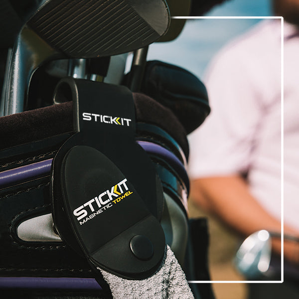 Black STICKIT magnetic towel holder with gray towel, designed for golf bags or outdoor sports equipment.