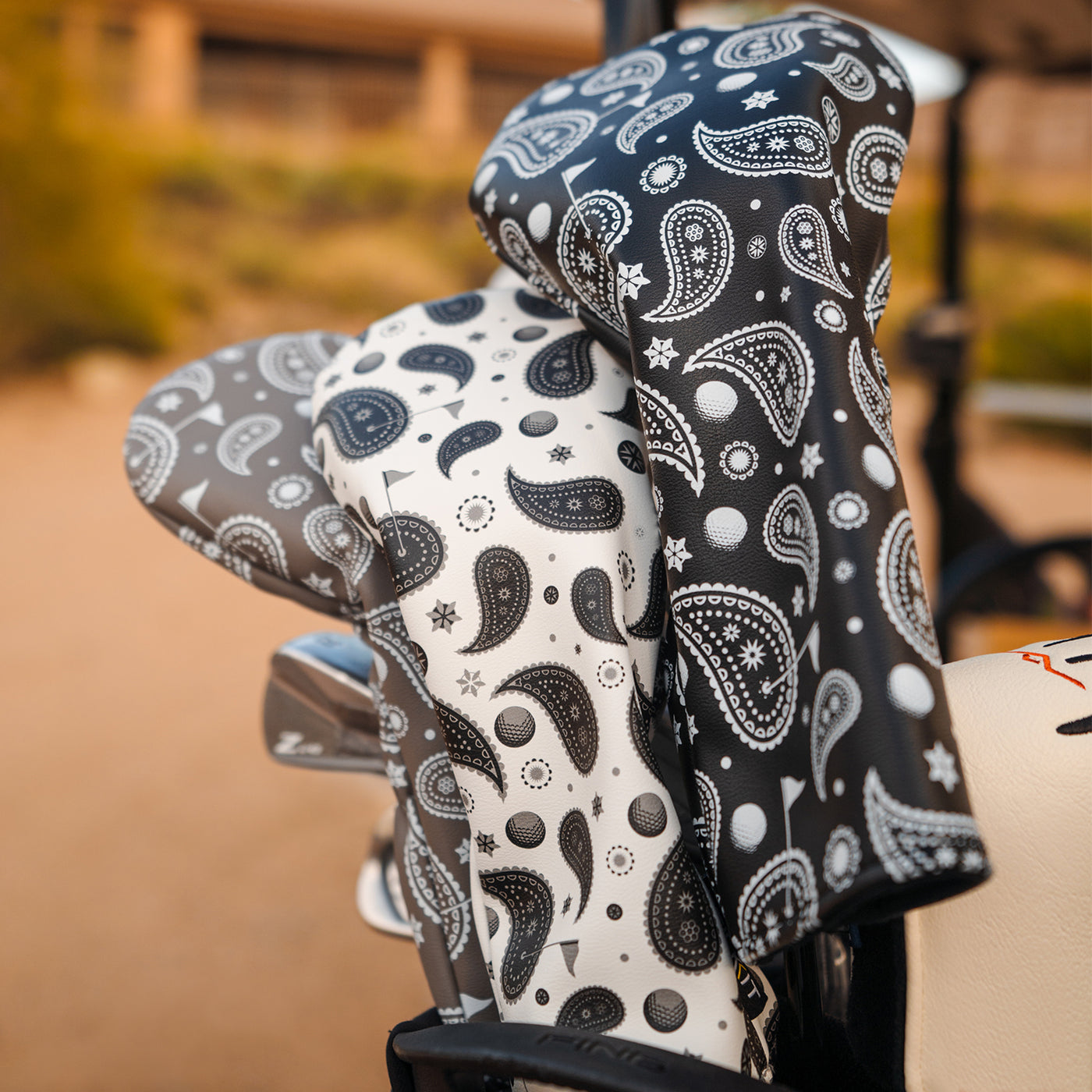 Black and white paisley-patterned golf club head covers made from durable material, perfect for stylish protection.
