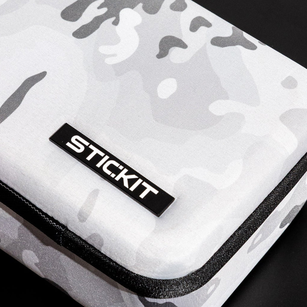 White camo-patterned hard case with black zipper and STICKIT logo, perfect for protective storage.